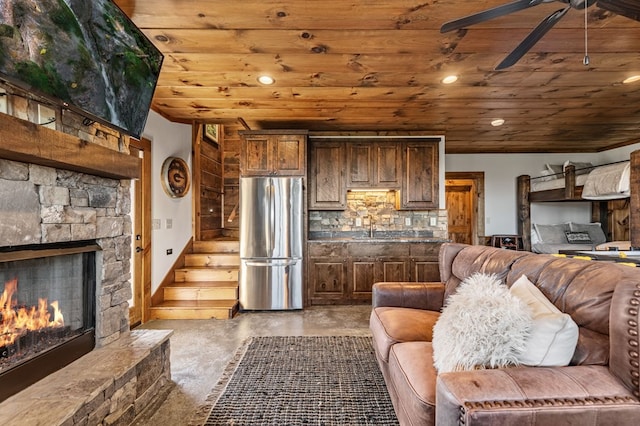 living room featuring sink, ceiling fan, wood ceiling, and a stone fireplace