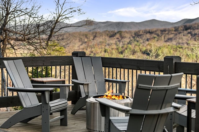 wooden deck with an outdoor fire pit and a mountain view