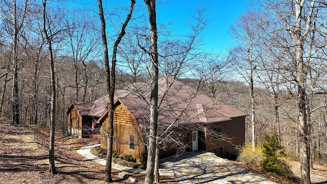 view of front of property with driveway and a wooded view