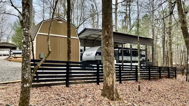 exterior space featuring a detached carport, fence, and an outbuilding