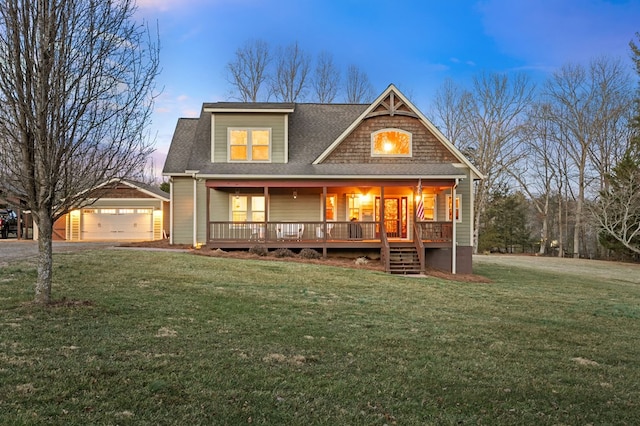 view of front facade with a porch, an outbuilding, a lawn, and a shingled roof