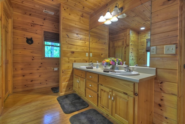 bathroom featuring a sink, wood finished floors, wood walls, double vanity, and wood ceiling