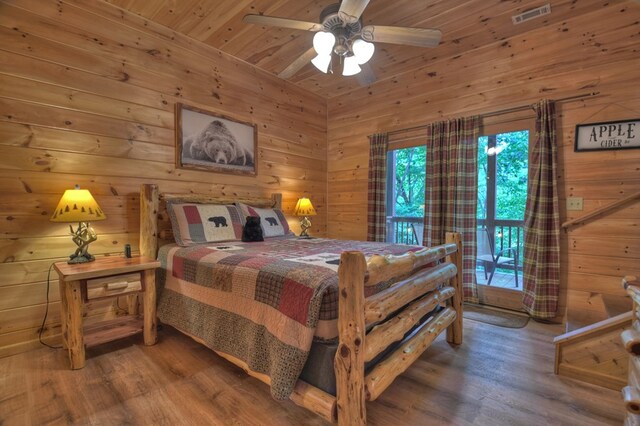 bedroom featuring visible vents, wood finished floors, and wood walls