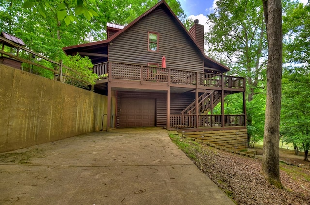 view of front of property with log veneer siding, a deck, driveway, an attached garage, and a chimney