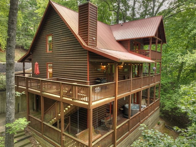 back of house featuring a wooden deck, a chimney, and metal roof