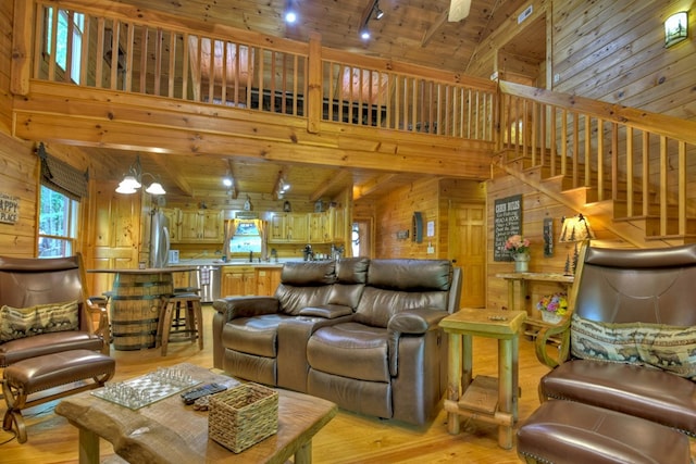 living area featuring stairway, wooden walls, light wood-style floors, wooden ceiling, and a notable chandelier