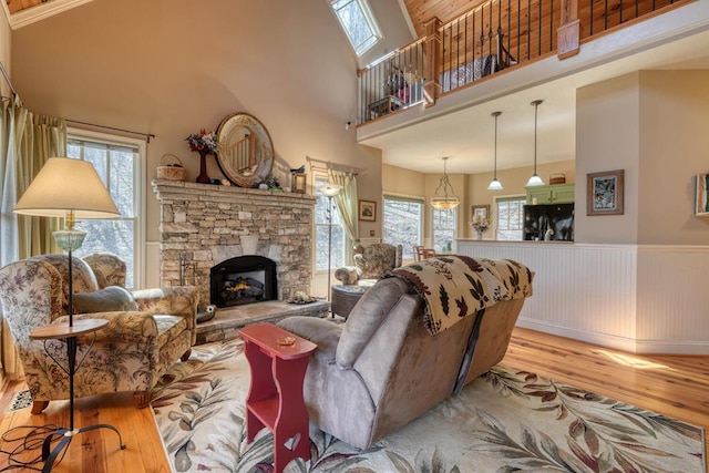 526 Garland Ridge Dr, Hayesville, NC 28904 - living room featuring a wainscoted wall, a towering ceiling, wood finished floors, and a stone fireplace