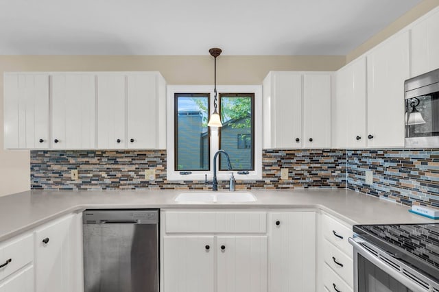 kitchen featuring stainless steel appliances, a sink, light countertops, tasteful backsplash, and white cabinetry