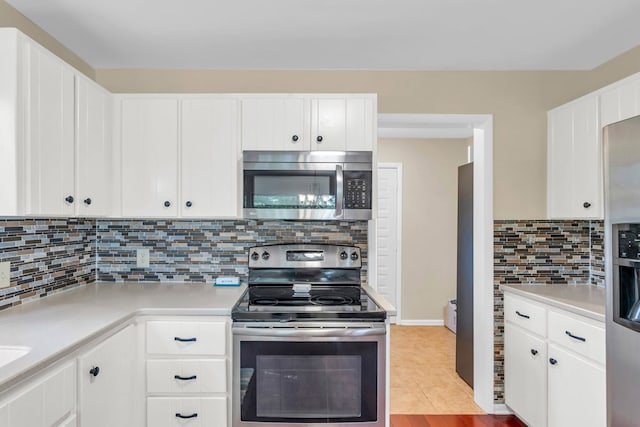 kitchen featuring appliances with stainless steel finishes, light countertops, decorative backsplash, and white cabinets