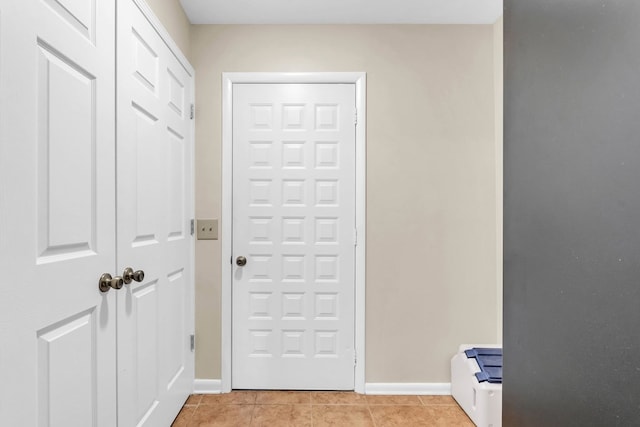 doorway with baseboards and light tile patterned floors