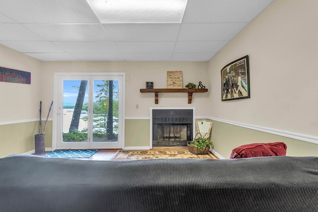 living room with a drop ceiling, a fireplace, baseboards, and carpet flooring