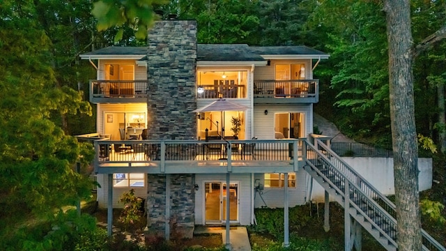 rear view of property with a balcony, stairway, and a chimney
