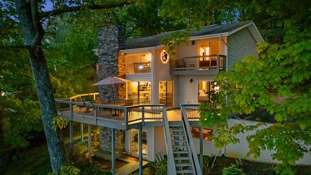 rear view of house with a balcony, stairs, a chimney, and a deck