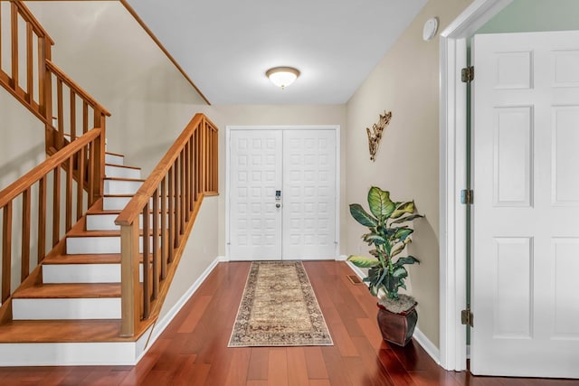 foyer entrance featuring stairs, wood finished floors, and baseboards