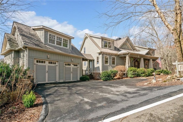 view of front facade featuring aphalt driveway, board and batten siding, a garage, and roof with shingles