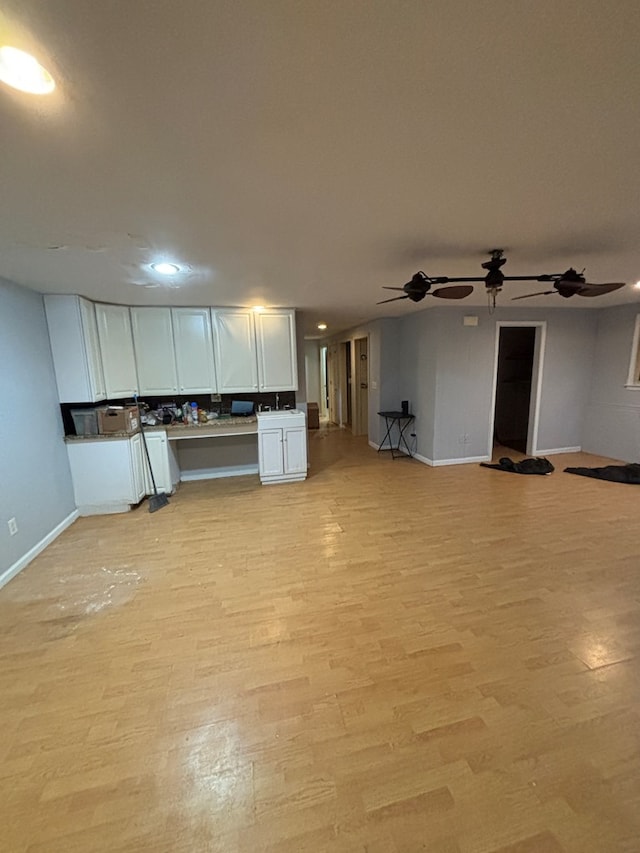 kitchen with light wood-type flooring, open floor plan, baseboards, and white cabinets