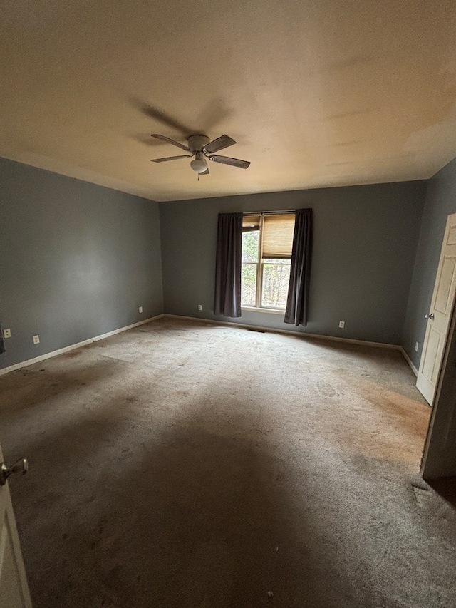 carpeted empty room featuring baseboards and ceiling fan