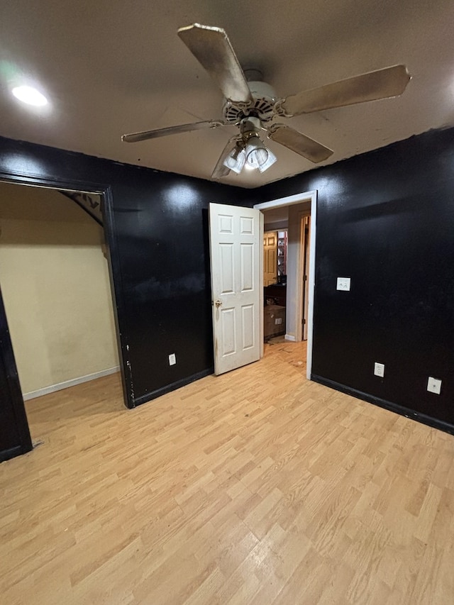 unfurnished bedroom with ceiling fan, baseboards, and light wood-style flooring