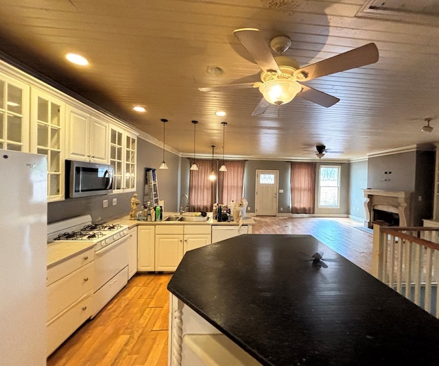 kitchen featuring stainless steel microwave, gas range gas stove, open floor plan, a peninsula, and freestanding refrigerator