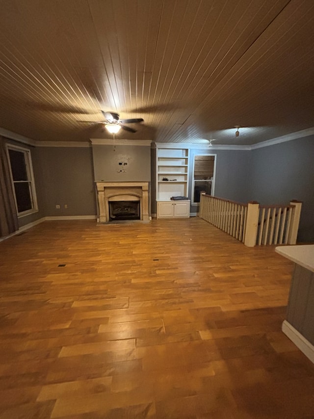 unfurnished living room with wood ceiling, ornamental molding, a fireplace, wood finished floors, and a ceiling fan