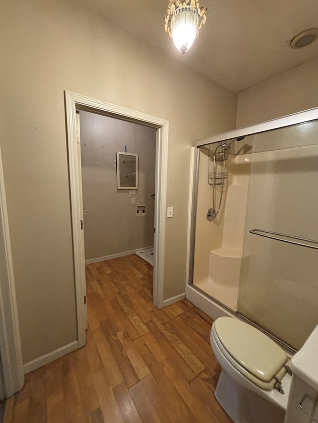 full bathroom featuring a shower stall, toilet, baseboards, and wood finished floors