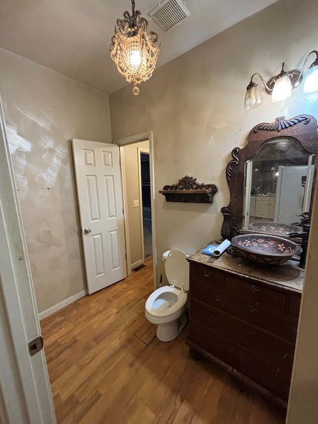 bathroom with visible vents, toilet, wood finished floors, baseboards, and vanity