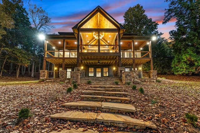 back house at dusk featuring ceiling fan and a balcony