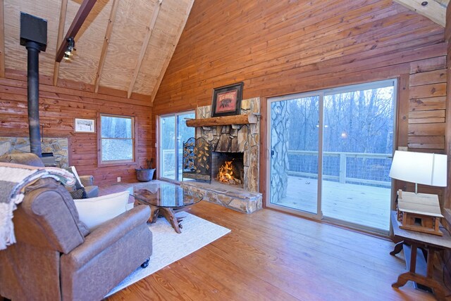 living room featuring high vaulted ceiling, a wood stove, plenty of natural light, beamed ceiling, and hardwood / wood-style floors