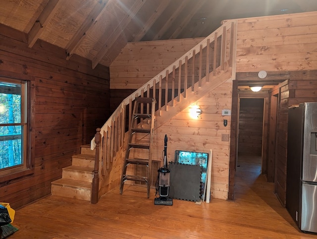 stairway with lofted ceiling with beams, hardwood / wood-style flooring, wood ceiling, and wood walls