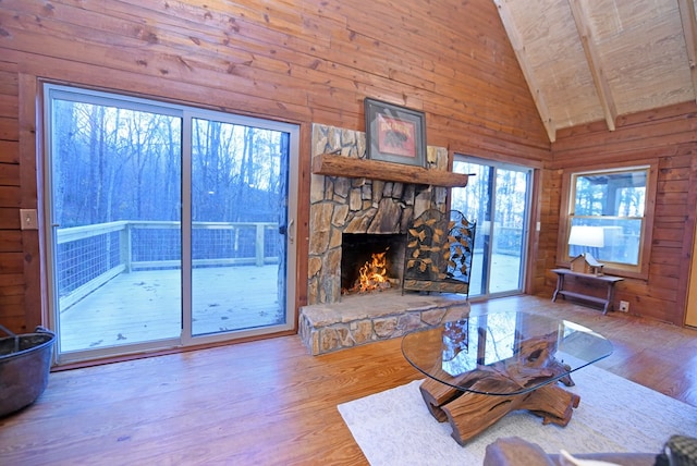 unfurnished living room featuring a stone fireplace, wood walls, wooden ceiling, hardwood / wood-style flooring, and beam ceiling