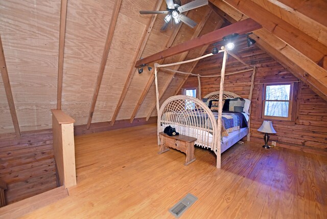 bedroom featuring ceiling fan, vaulted ceiling, hardwood / wood-style floors, and wooden walls