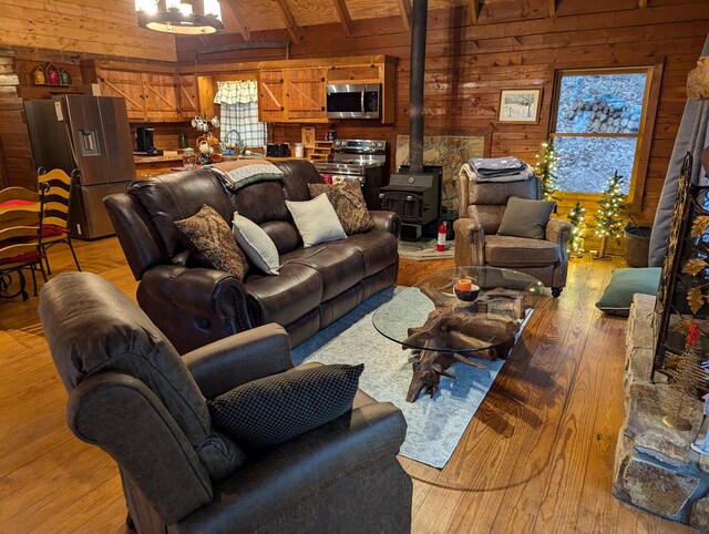 living room featuring wooden walls, light hardwood / wood-style flooring, and a wood stove