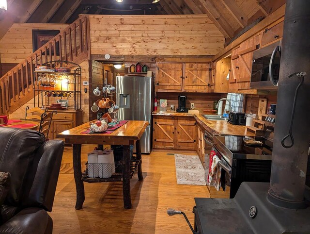 kitchen featuring wood walls, lofted ceiling with beams, sink, wood ceiling, and stainless steel appliances