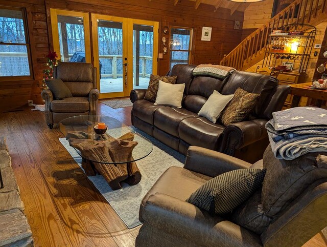 living room with french doors, wood-type flooring, beam ceiling, and wood walls