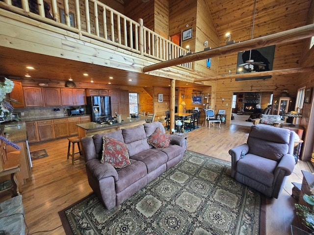 1102 Summit Way, Blairsville, GA 30512 - living area featuring a lit fireplace, light wood-type flooring, wood walls, and a towering ceiling