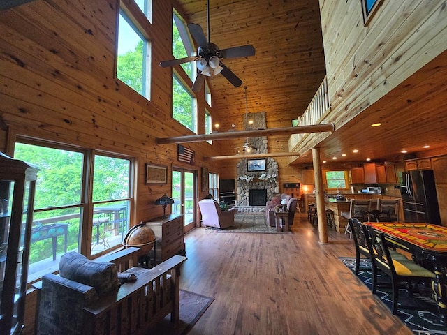 1102 Summit Way, Blairsville, GA 30512 - living room featuring a high ceiling, ceiling fan, hardwood / wood-style flooring, a stone fireplace, and wood walls