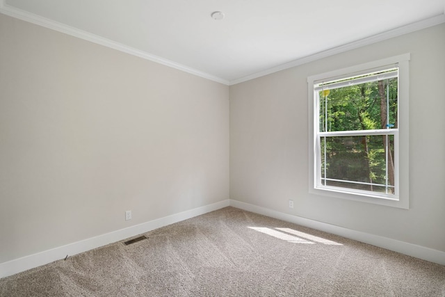 carpeted spare room featuring visible vents, baseboards, and crown molding