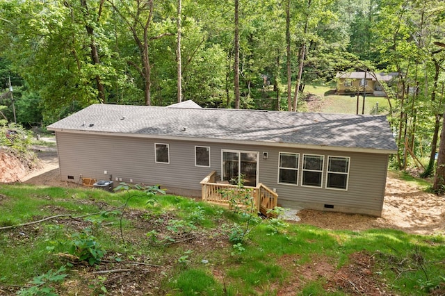 rear view of house featuring crawl space, a shingled roof, a wooded view, and a deck