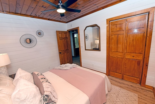 bedroom featuring ceiling fan, wooden ceiling, wooden walls, and light hardwood / wood-style flooring