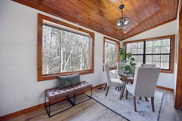 dining area with an inviting chandelier, light hardwood / wood-style flooring, wood walls, lofted ceiling, and wood ceiling