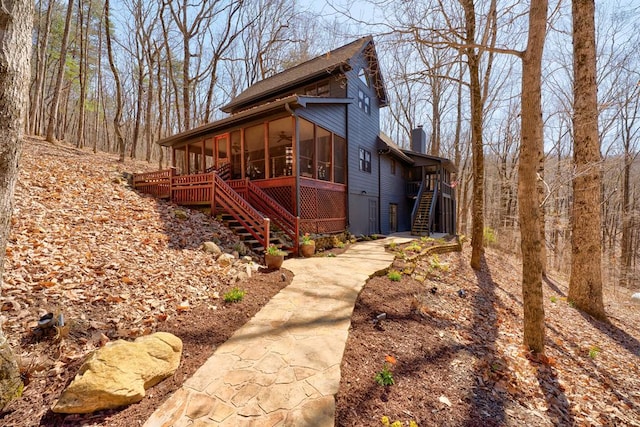 view of home's exterior with stairway, a chimney, and a sunroom