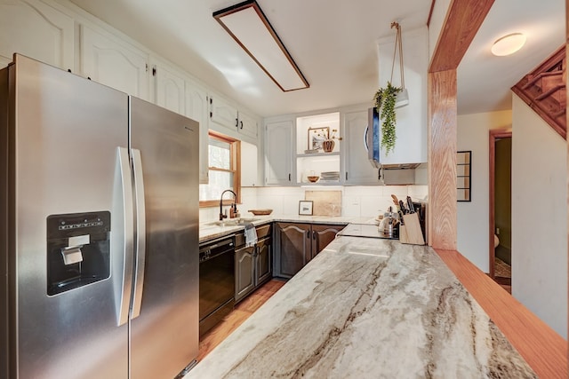 kitchen with black dishwasher, light stone counters, white cabinetry, stainless steel refrigerator with ice dispenser, and a sink