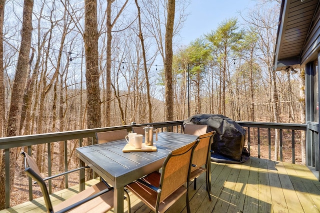 wooden deck featuring outdoor dining area and a grill