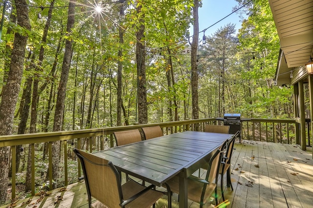 wooden terrace with outdoor dining space and grilling area