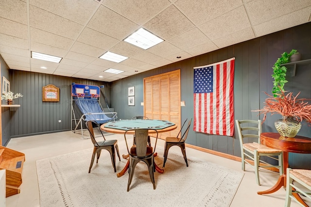 game room featuring a paneled ceiling and concrete floors