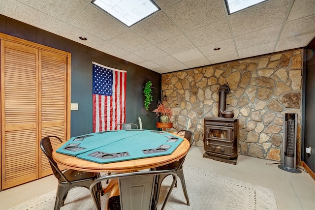 game room featuring a paneled ceiling, wood walls, and a wood stove