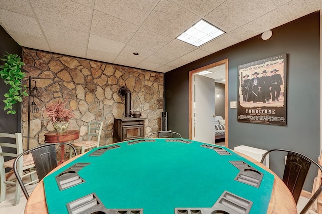 game room with a paneled ceiling and a wood stove