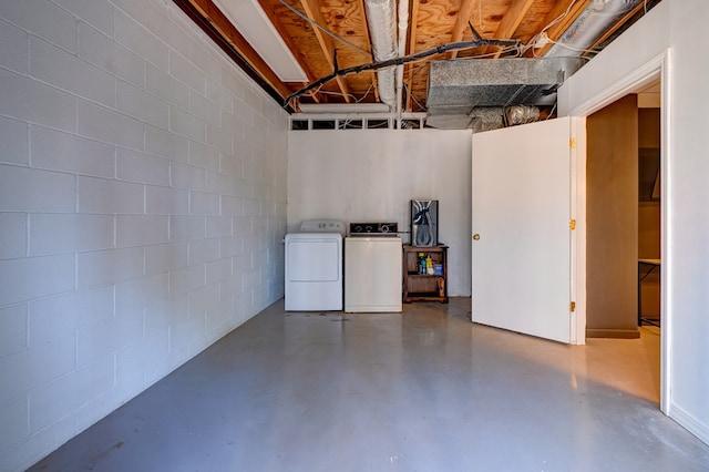 unfinished basement featuring concrete block wall and washer and clothes dryer