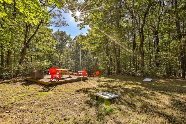 view of yard with a wooden deck and a view of trees