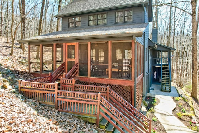 view of front of house featuring a chimney, a sunroom, roof with shingles, and stairway